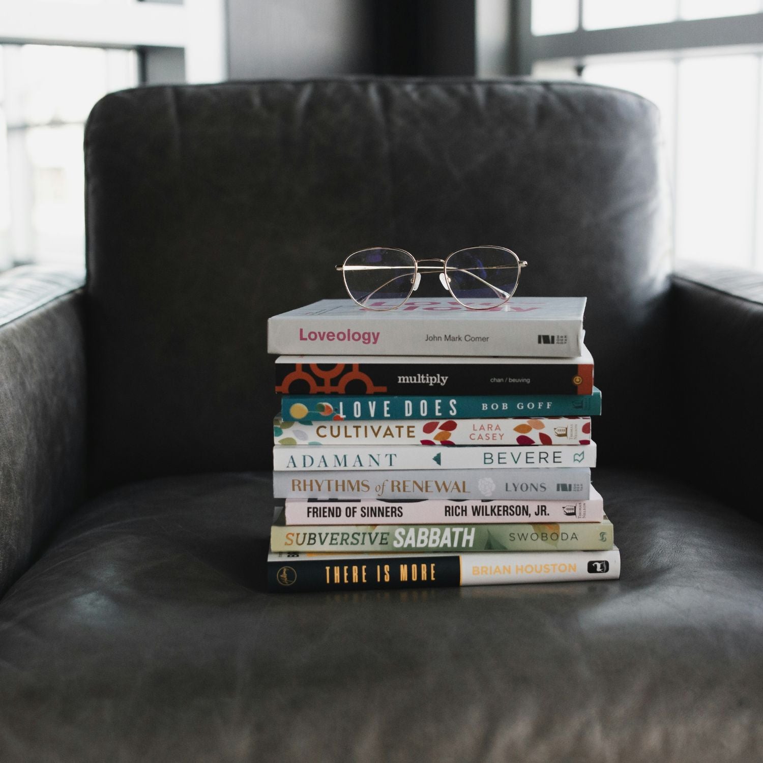 Stack of books with glasses on a dark leather chair