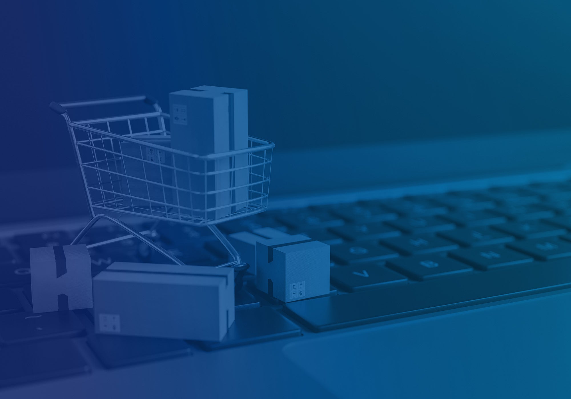 A miniature shopping cart made of wire and small cardboard boxes sits on a laptop keyboard, with a dark blue overlay across the entire scene.