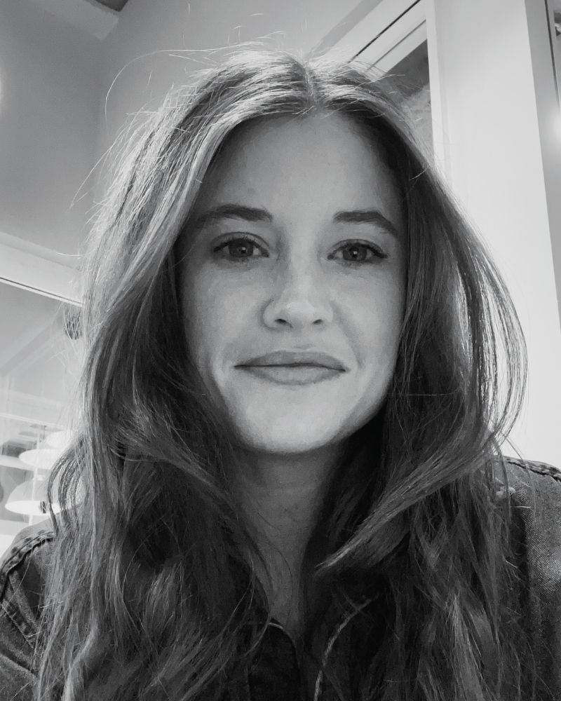 Black and white photo of a woman with long hair indoors.