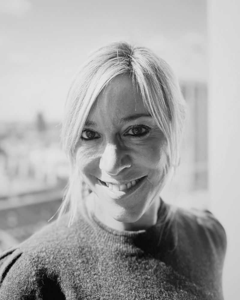 Black and white photo of a person with light hair and a textured sweater.