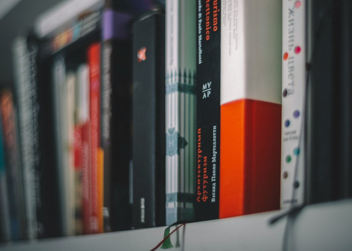 An upclose photo of a out of focus bookshelf with the titles obscured