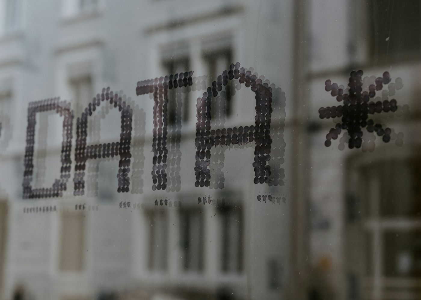 Window with 'DATA' spelled out in black letters, blurred background of a building.