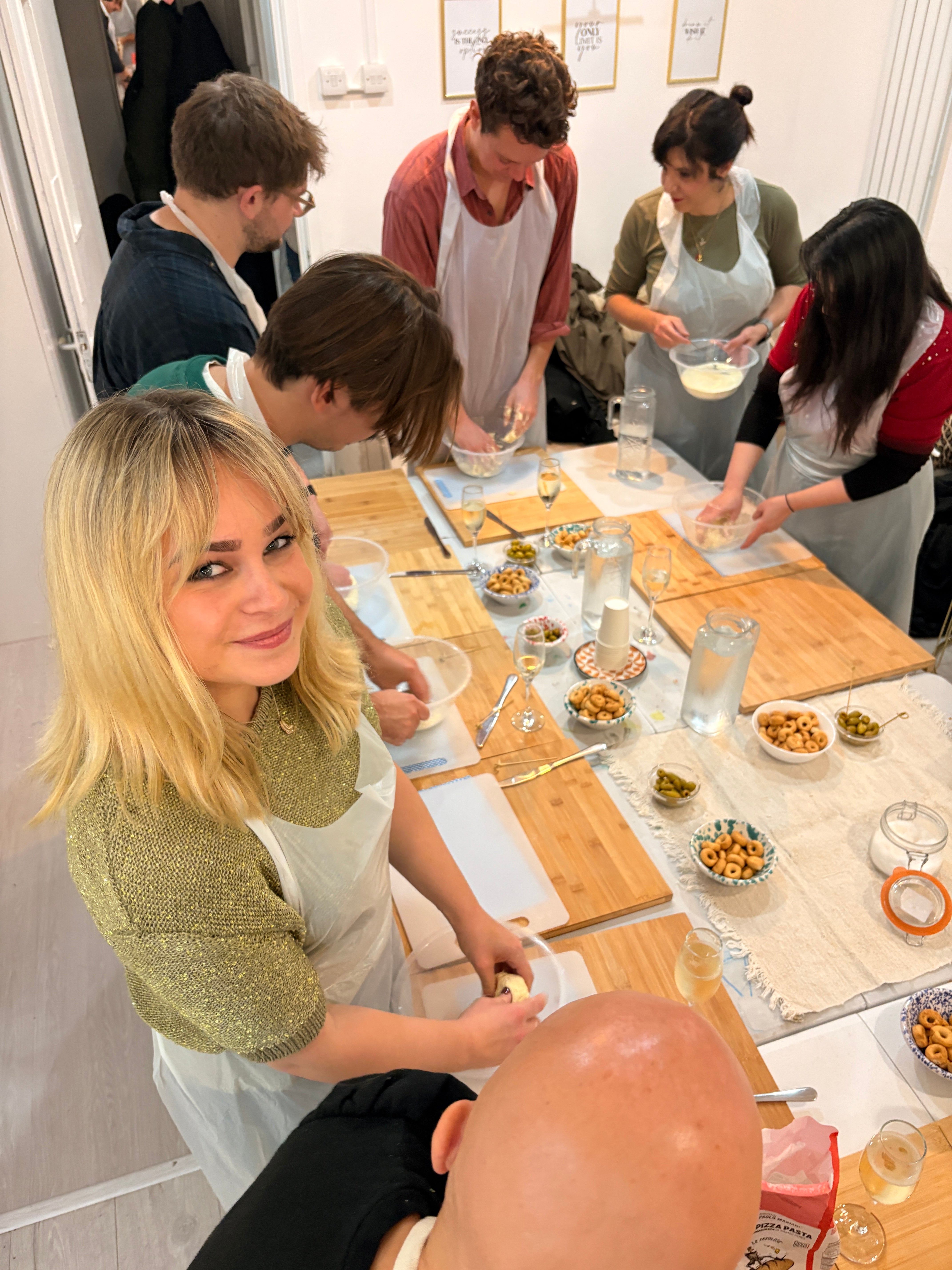 Group of people gathered around a dining table with food and drinks.