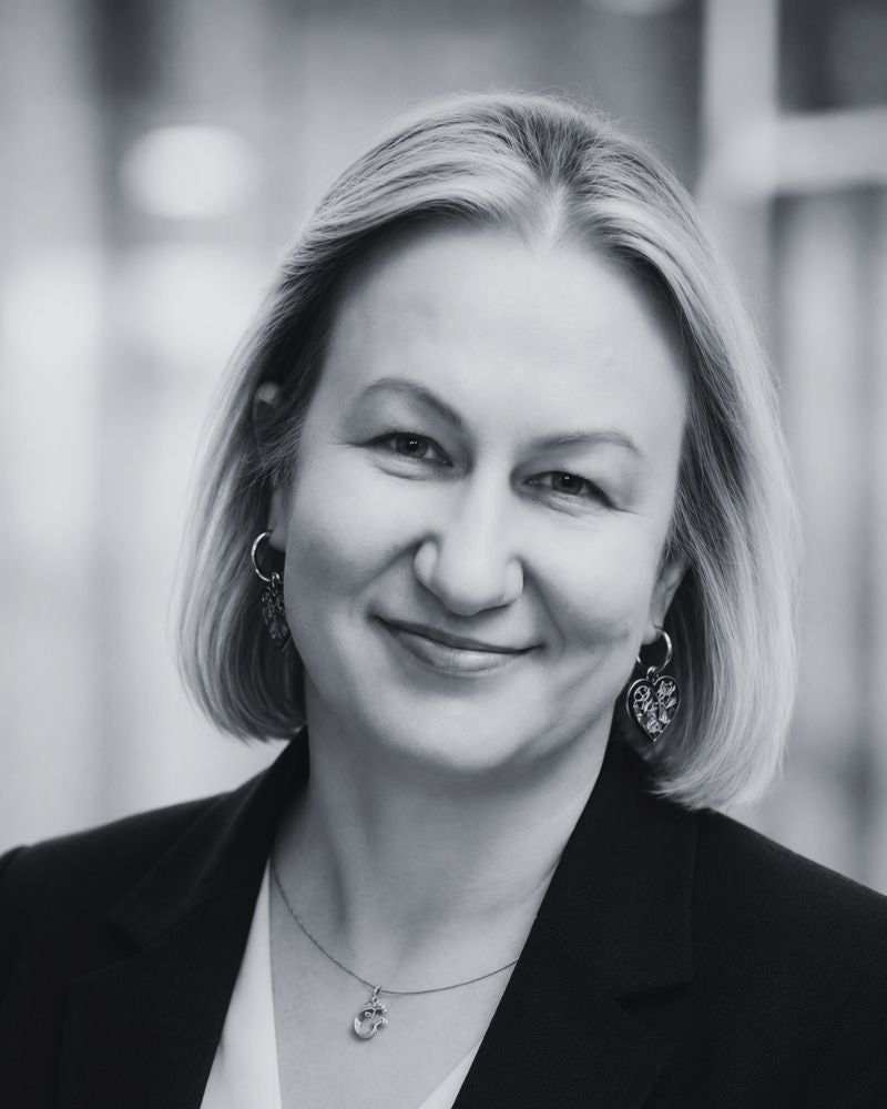 Black and white portrait of a woman with short hair, wearing a black blazer.